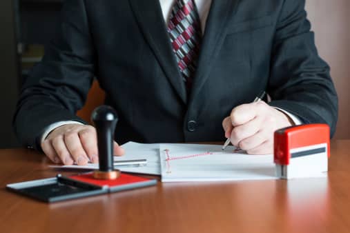 A Car Accident Attorney sits at his desk preparing papers for a client